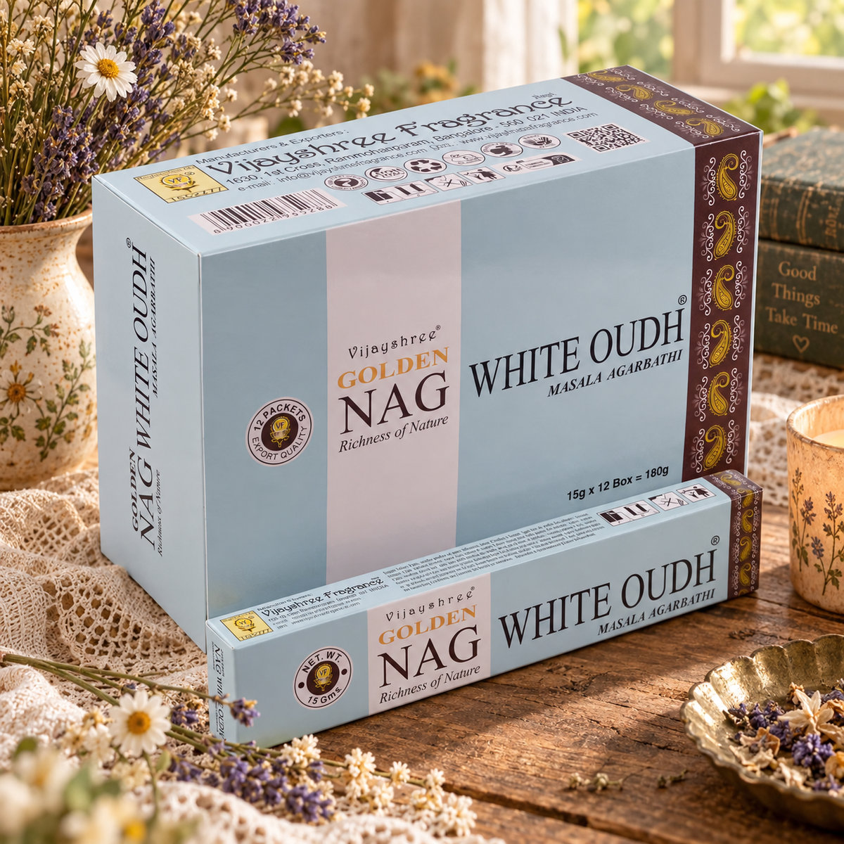 Confezioni azzurro chiaro di incenso Golden Nag White Oudh, su un tavolo con fiori e lavanda.
