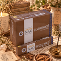 Confezioni marroni di incenso Golden Nag Sandalwood, con pezzetti di legno e un bastoncino acceso.